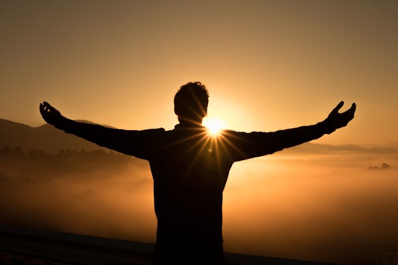 Silhouette of a man with arms outstretched at sunrise